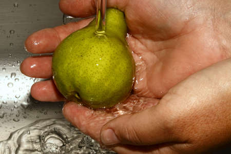 washing a green pear under running waterの写真素材