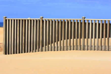 wind blown sand against a concrete fenceの写真素材