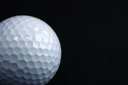 white golf ball on a black backgroundの写真素材