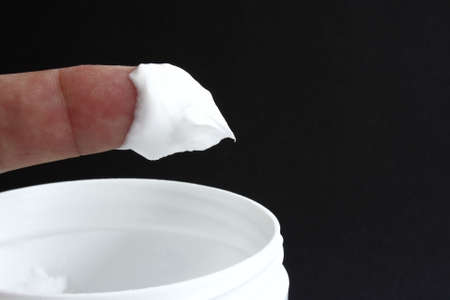 finger of white cream on a black backgroundの写真素材