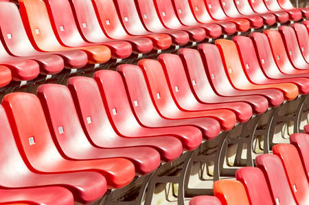 rows of red chairs in a sports stadium on a hot summers dayの写真素材