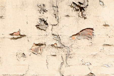 old brick cracked brick wall with broken plaster and signs of decayの写真素材