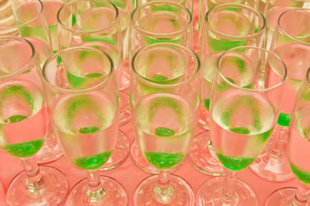 A shallow depth of field of rows of cocktail glasses filled with clear alcohol and green cherriesの写真素材