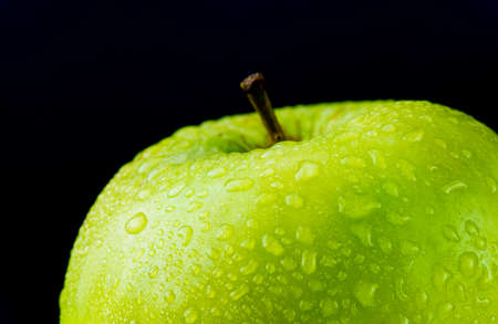 Juicy green apple with water droplets on a black backgroundの写真素材