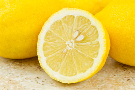 sliced lemon with pips isolated on a brown textured background
