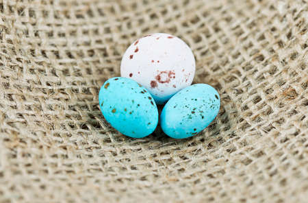 one white and two blue speckled eggs on a burlap hessian backgroundの写真素材