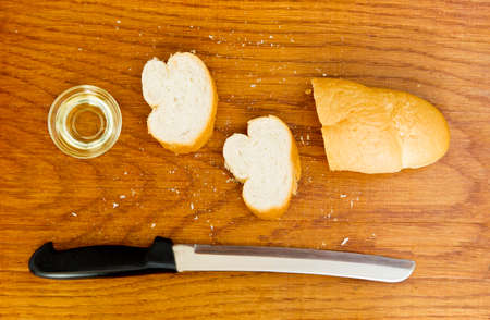 wooden board with French loaf bread and extra virgin olive oil