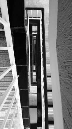 Abstract view of a stairwell with black banisters and tiled floors