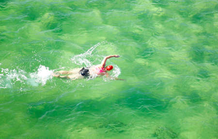 Lady swimmer wearing a swim cap having a workout in the beautiful ocean 