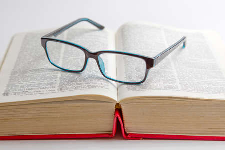 green coloured reading glasses placed on a book isolated on a white backgroundの写真素材