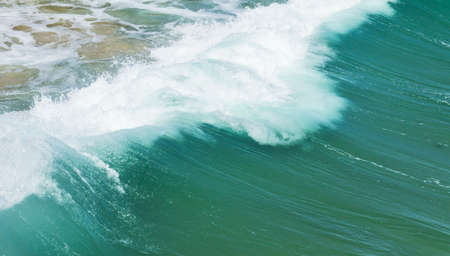 back of a dramatic wave as it hits the sandy shore on a hot summers dayの写真素材