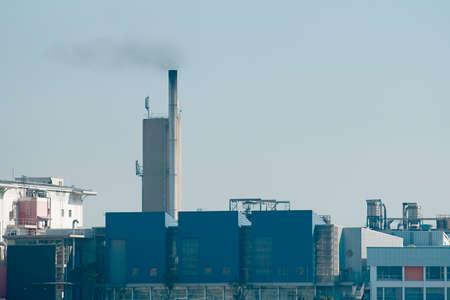 Large dirty chemical Factory in an urban area creating smoke from a tall chimney