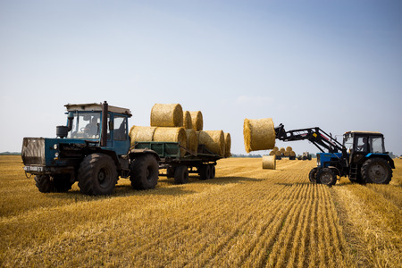 Vinnitsa,Ukraine - July 26,2016.huge tractor collecting haystack in the field at nice blue sunny...
