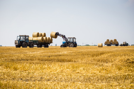 Vinnitsa,Ukraine - July 26,2016.huge tractor collecting haystack in the field at nice blue sunny...