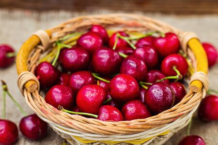 red cherries in basket, ?herry basket, red ?herries on wooden table with water drops macro background, red cherries on a brown background, basket with cherriesの写真素材