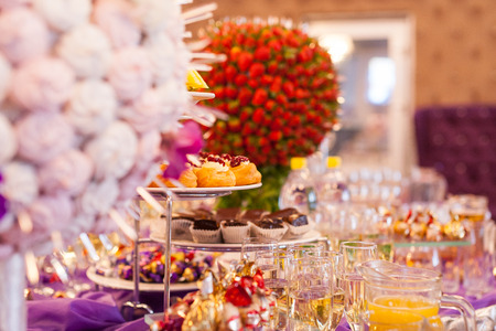 stylish luxury decorated candy bar for the celebration of a wedding of happy couple, cathering in the restaurant, Sweet holiday buffet with cupcakes and other desserts.の写真素材