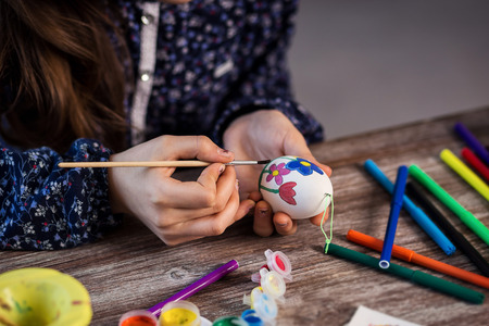 colouring eggs for eastertime at home.Happy easter! A mother and her daughter painting Easter eggs. Happy family preparing for Easter.decorating Easter eggs, children's hands hold a paintbrush and paintの写真素材