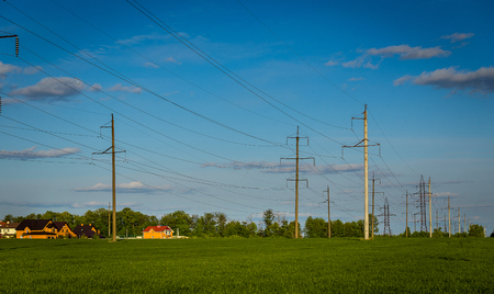background of agricultural rapeseed fields and concrete electricity pole on background of blue sky.Electrical poles with a green field and cloudy sky,High voltage poleの写真素材