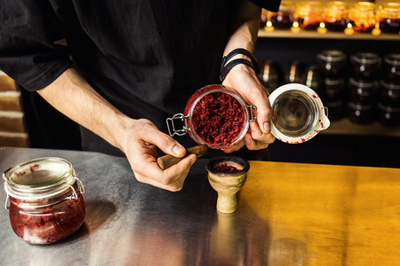 Shisha hookah preparing by barman. Bartender lays tobacco for smokingの写真素材