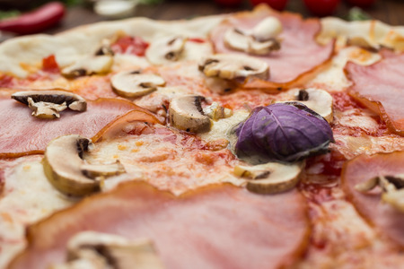 Delicious italian pizza with ham and mushrooms on wooden backgroundの写真素材