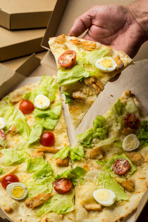 Pizza Caesar with chicken and tomatoes in box on wooden backgroundの写真素材