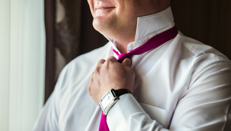 man in shirt dressing up and adjusting tie on neck at homeの写真素材