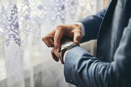 businessman checking time on his wrist watch, man putting clock on hand,groom getting ready in the...