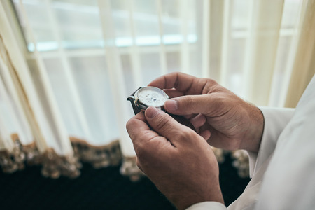businessman checking time on his wrist watch, man putting clock on hand,groom getting ready in the morning before wedding ceremonyの写真素材