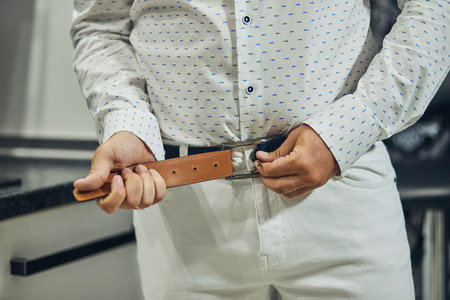Businessman putting on a belt, fashion and clothing concept,groom getting ready in the morning before ceremonyの写真素材