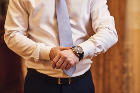 businessman checking time on his wrist watch, man putting clock on hand,groom getting ready in the morning before wedding ceremony. Men Fashionの写真素材