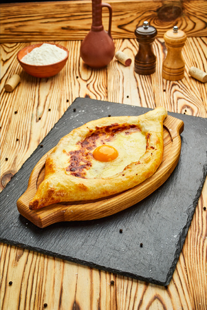 Ajarian Khachapuri traditional Georgian cheese pastry with eggs on cutting board. Homemade baking. Open pie with mozzarellaの写真素材