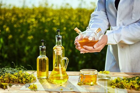 rapeseed oil bottle in hand of an agronomist or biologist on background rape fieldの写真素材