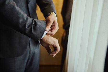 Businessman wears a jacket,male hands closeup,groom getting ready in the morning before wedding ceremonyの写真素材