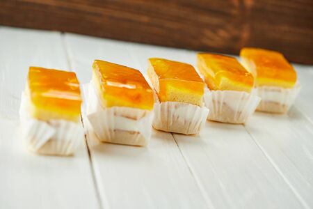 Orange jelly sponge cakes on wooden background