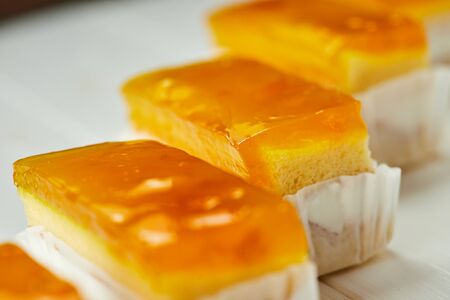 Orange jelly sponge cakes on wooden background