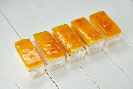 Orange jelly sponge cakes on wooden background