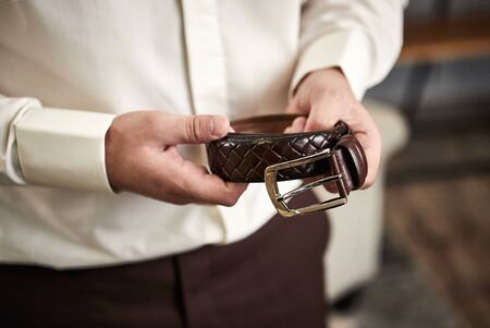 Businessman putting on a belt, fashion and clothing concept,groom getting ready in the morning before ceremonyの写真素材