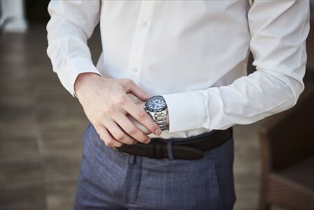 businessman checking time on his wrist watch, man putting clock on hand,groom getting ready in the...