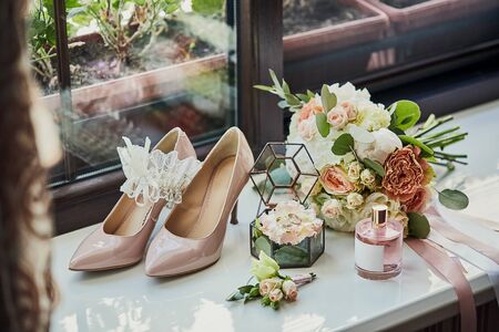 bridal accessories such as shoes, bouquet , ring and perfume lie on a tableの写真素材