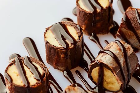 Delicious healthy homemade dessert of bananas, chocolate and cream cheese or ricotta. Banana rolls on a white plate. Treats for kidsの写真素材