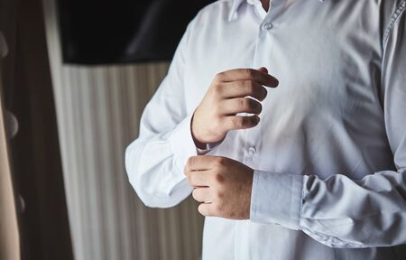 businessman dresses white shirt, male hands closeup,groom getting ready in the morning before...