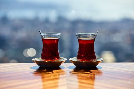 Two cups (armudas) of traditional Turkish tea are served on a table against the background of the Istanbul cityscapeの写真素材