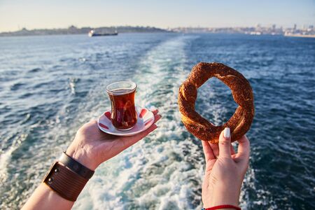 A cup (armud) of traditional Turkish tea and Simitci (a round bagel with sesame seeds) in hand...