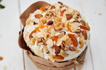 Easter cake decorated by nuts and dried fruits on white wooden background, Traditional Kulich, Paska...