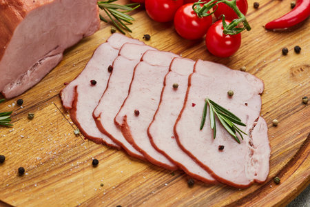 Sliced ham with spices, lettuce, avocado and tomatoes on wooden cutting board. Ð¡old meat plate....