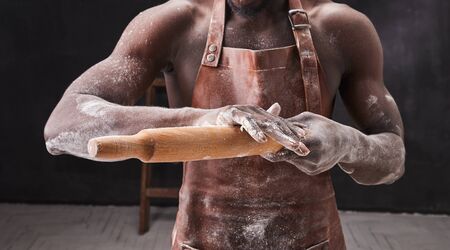 Dark skin baker man kneads Dough in the kitchen. Pastry chef prepares yeast dough for pizza pasta. の写真素材