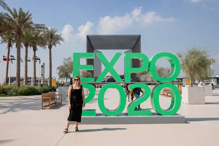 Dubai, United Arab Emirates - November 06, 2021: Woman tourist near Entrance gate of Terra Sustainability Pavilion at the EXPO 2020 in the United Arab Emirates. Green Logo sign EXPO 2020のeditorial素材
