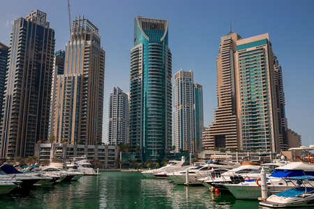 Dubai, UAE - November 06, 2021: Luxury Dubai Marina skyscrapers, cruise boat and promenade in...