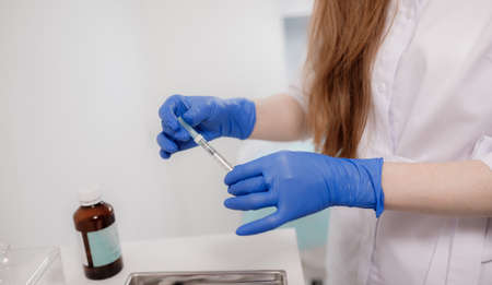 Girl beautician holds cosmetic tools - syringes, ampoules, creams and skin care products