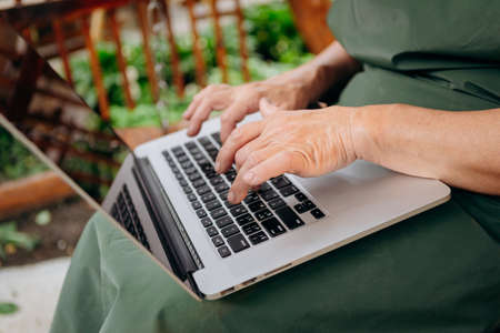 Senior Female hands type text on laptop keyboardの写真素材